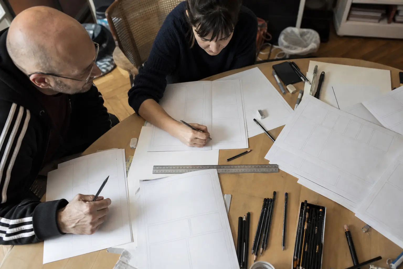 Des planches de bande dessinée et des crayons posés sur une table de travail