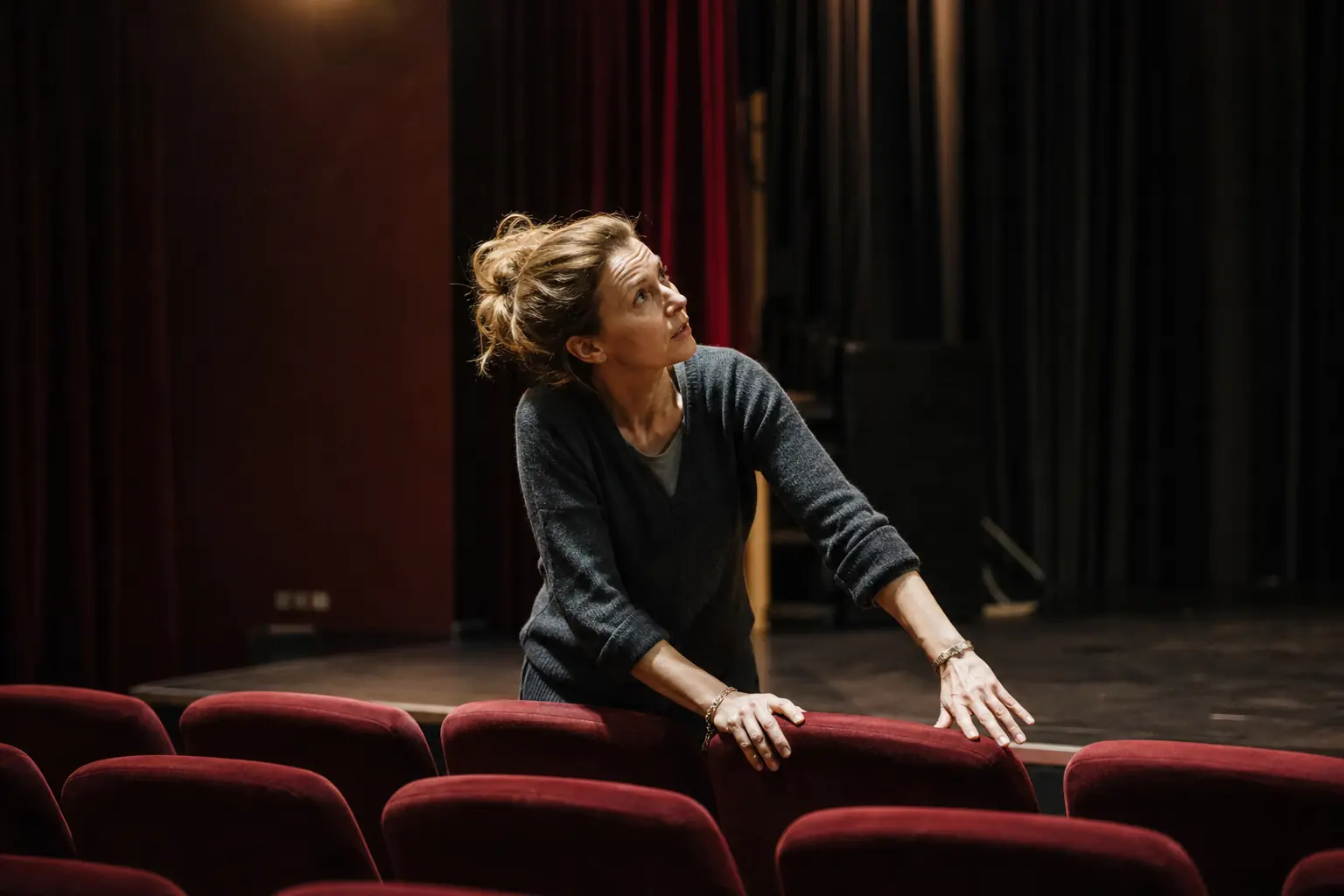 Une artiste répète sur la scène d'un petit théâtre, dans la lumière des projecteurs