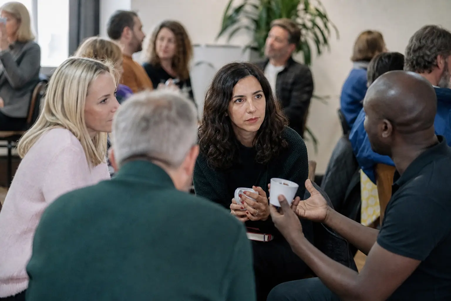 Plusieurs adultes discutent lors d'un événement associatif dans une salle claire